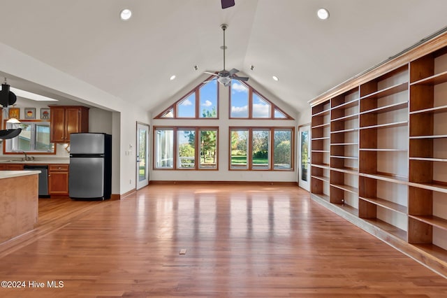 unfurnished living room featuring light wood-type flooring, high vaulted ceiling, ceiling fan, and sink