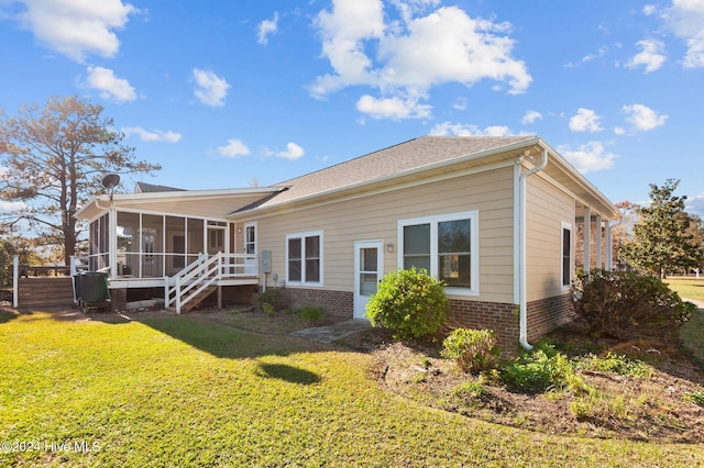 rear view of property featuring a sunroom and a lawn