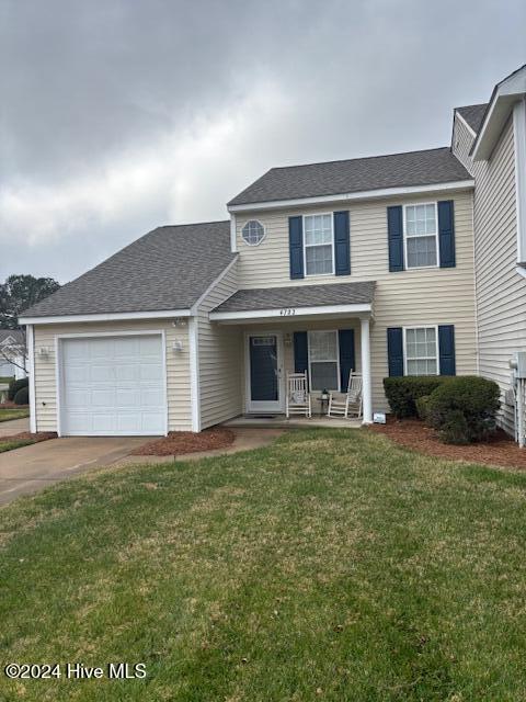 view of front of house featuring a front lawn, covered porch, and a garage