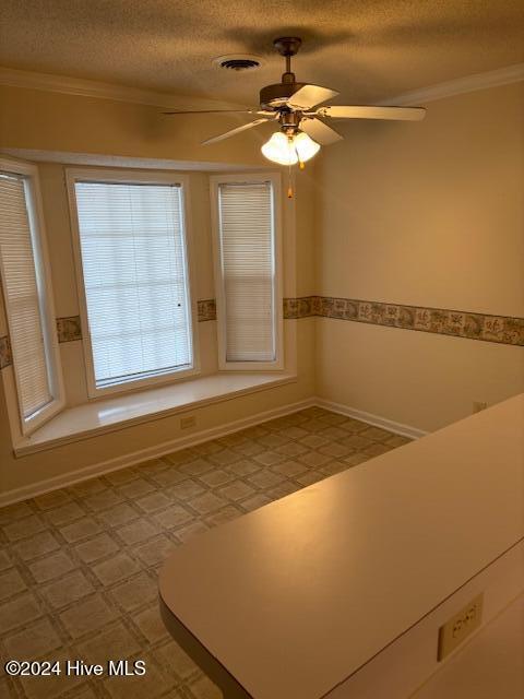 unfurnished room with ceiling fan, ornamental molding, and a textured ceiling
