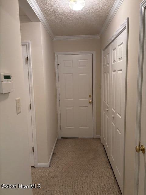 hallway featuring light carpet, crown molding, and a textured ceiling