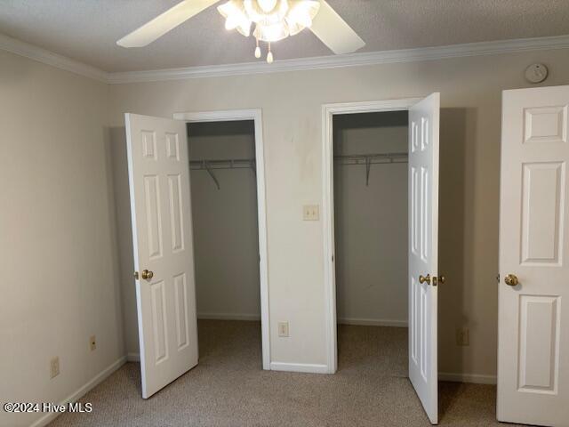 unfurnished bedroom featuring ceiling fan, crown molding, and light carpet