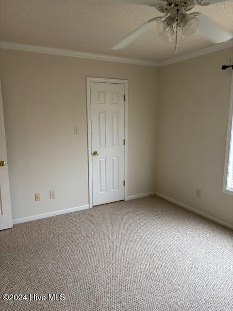 carpeted spare room with a textured ceiling, ceiling fan, and ornamental molding