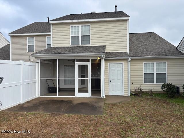 back of property with a yard and a sunroom