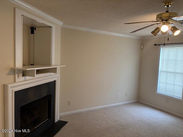 unfurnished living room featuring carpet flooring, a textured ceiling, ceiling fan, and crown molding