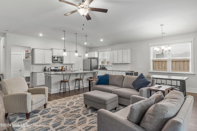 living room with dark hardwood / wood-style flooring, plenty of natural light, and ceiling fan with notable chandelier