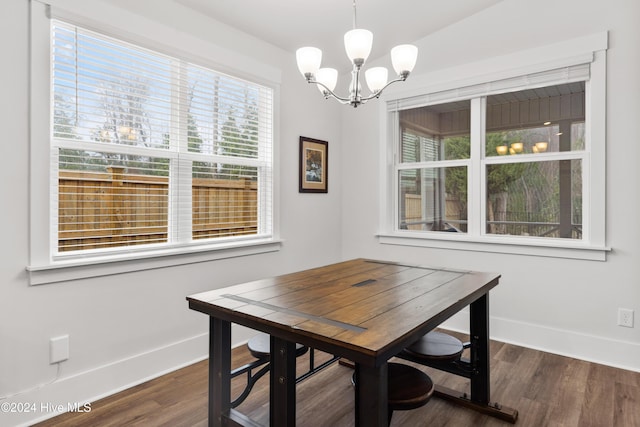 dining space with dark wood-type flooring and a notable chandelier