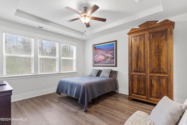 bedroom featuring a tray ceiling, ceiling fan, and hardwood / wood-style flooring