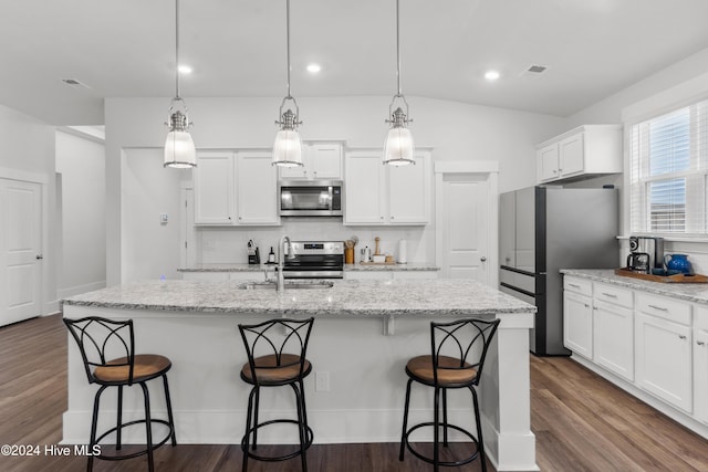 kitchen featuring sink, hanging light fixtures, stainless steel appliances, light stone counters, and an island with sink