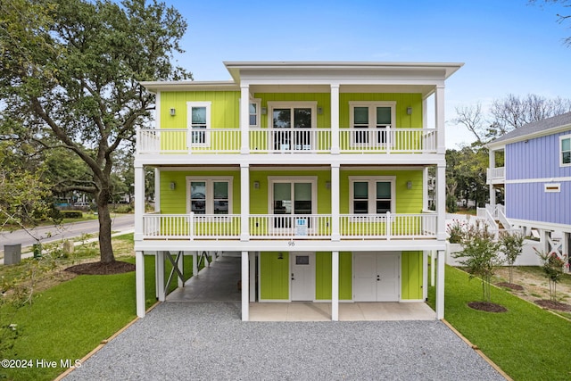 coastal home with a balcony and a front yard