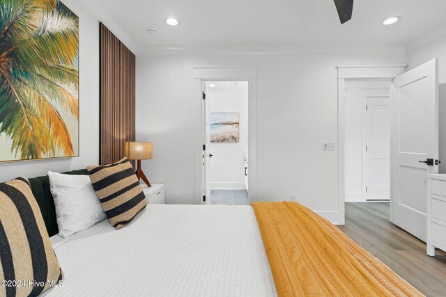 bedroom with ensuite bathroom, ceiling fan, and light hardwood / wood-style flooring