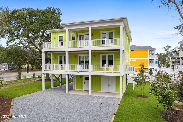 coastal inspired home featuring a balcony, french doors, and a front lawn