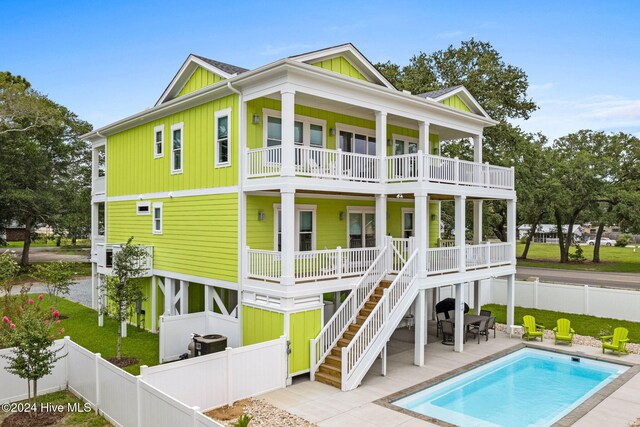 back of house featuring a patio area, a fenced in pool, and a balcony