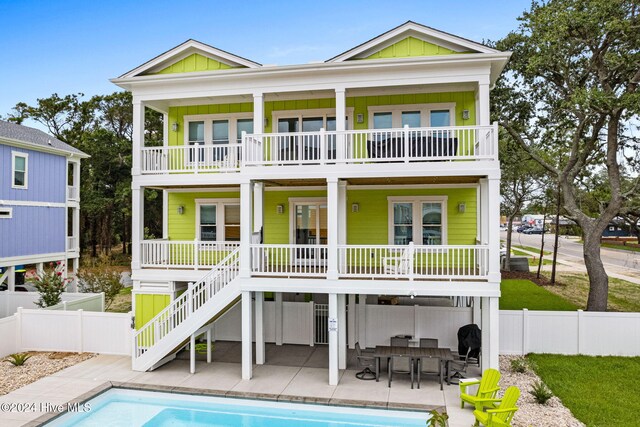 rear view of property featuring a patio, a balcony, and a fenced in pool