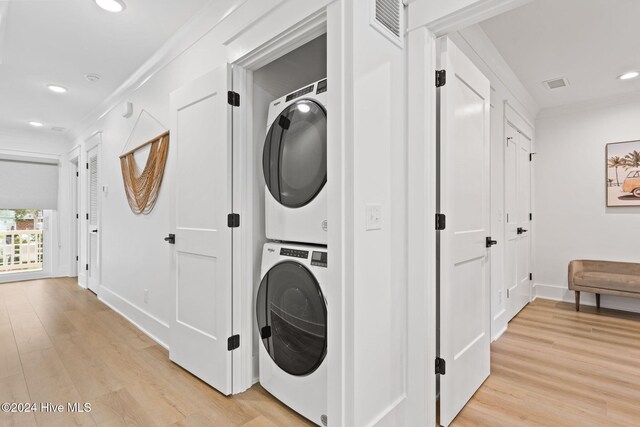 washroom featuring stacked washer and dryer, light hardwood / wood-style floors, and ornamental molding