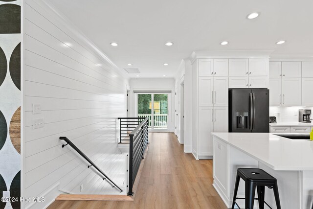 kitchen with white cabinetry, stainless steel fridge with ice dispenser, light hardwood / wood-style flooring, and a kitchen breakfast bar