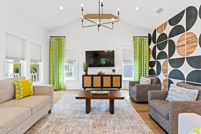 living room with a chandelier, wood-type flooring, and high vaulted ceiling