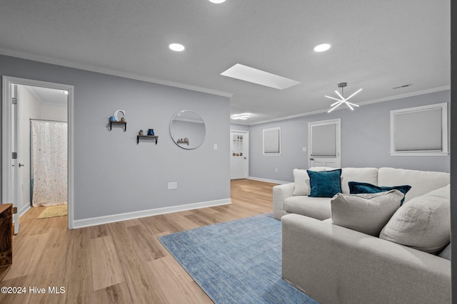 living room featuring a notable chandelier, a skylight, ornamental molding, and light hardwood / wood-style flooring