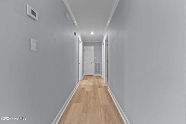 hallway with light hardwood / wood-style floors, a textured ceiling, and ornamental molding