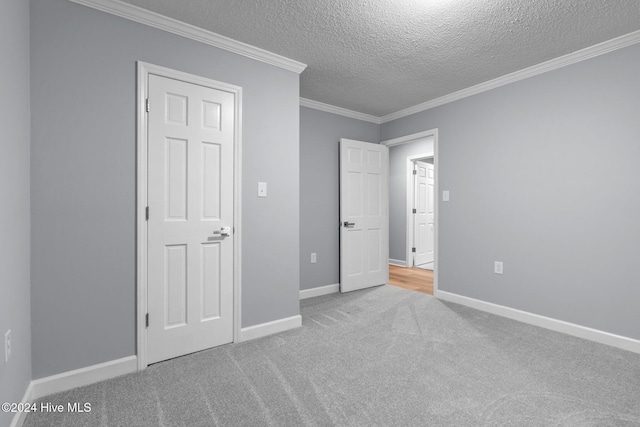 unfurnished bedroom featuring a textured ceiling, light colored carpet, and ornamental molding