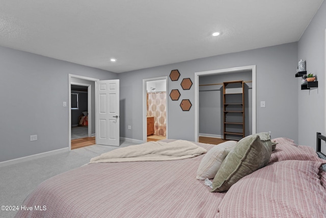 carpeted bedroom featuring a closet, a spacious closet, and ensuite bath