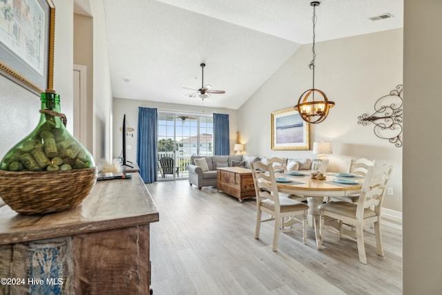 dining area featuring ceiling fan with notable chandelier, light wood-type flooring, and high vaulted ceiling