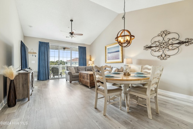 dining space featuring high vaulted ceiling, ceiling fan with notable chandelier, and light wood-type flooring