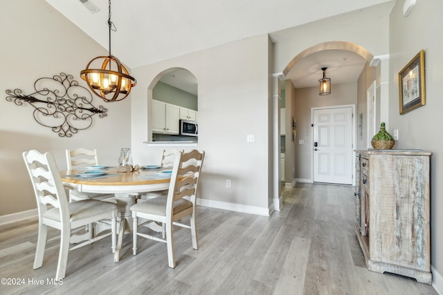 dining area with light hardwood / wood-style floors and an inviting chandelier