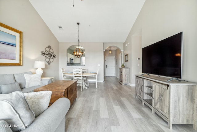 living room featuring a chandelier, light wood-type flooring, and vaulted ceiling