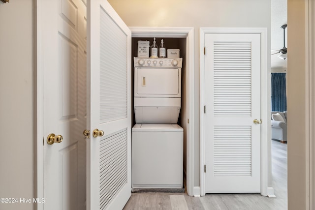 clothes washing area with light wood-type flooring, ceiling fan, and stacked washer / drying machine