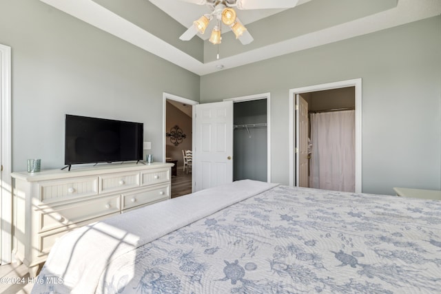 bedroom with ceiling fan, wood-type flooring, a tray ceiling, and a closet