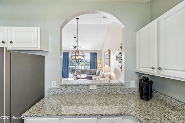 kitchen with light stone countertops, vaulted ceiling, a notable chandelier, white cabinetry, and stainless steel refrigerator