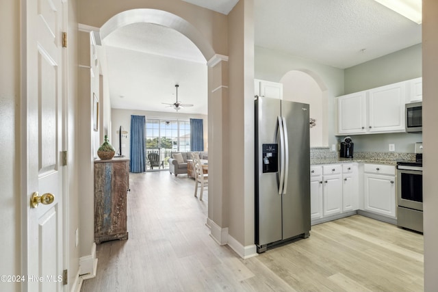 kitchen with light stone counters, light wood-type flooring, white cabinetry, and stainless steel appliances