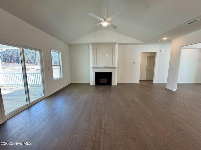 unfurnished living room with visible vents, baseboards, dark wood-type flooring, vaulted ceiling, and a fireplace