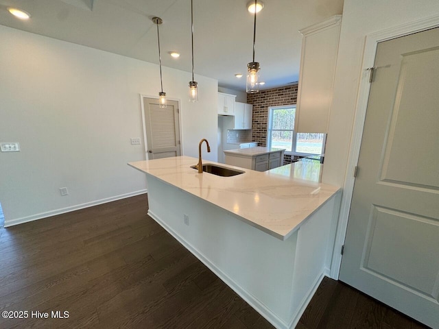 kitchen with dark wood-style flooring, white cabinetry, a sink, and light stone countertops