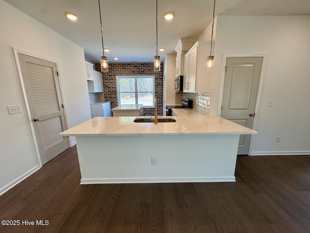 kitchen featuring decorative backsplash, appliances with stainless steel finishes, dark wood-style flooring, a peninsula, and white cabinetry