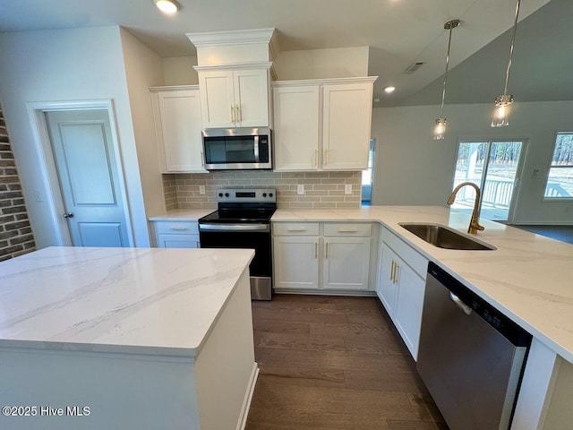 kitchen with stainless steel appliances, light stone counters, a sink, and white cabinetry