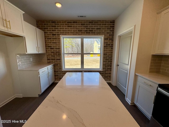 kitchen featuring brick wall, visible vents, decorative backsplash, and light stone counters