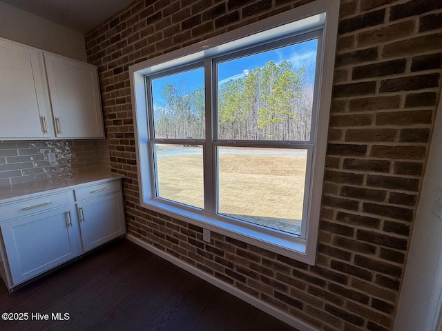 interior space featuring brick wall and dark wood-type flooring