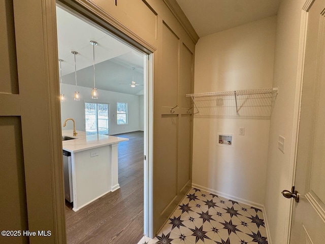 laundry room featuring laundry area, baseboards, hookup for a washing machine, light floors, and a sink