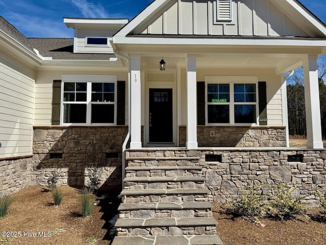 view of exterior entry with stone siding, a porch, board and batten siding, and a shingled roof