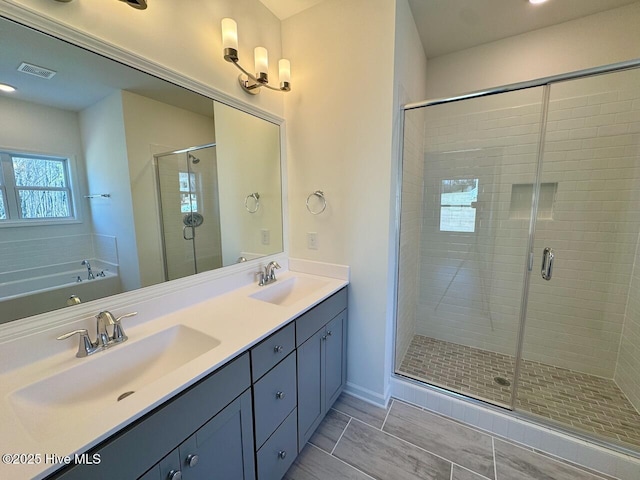 full bath featuring double vanity, a sink, visible vents, and a shower stall