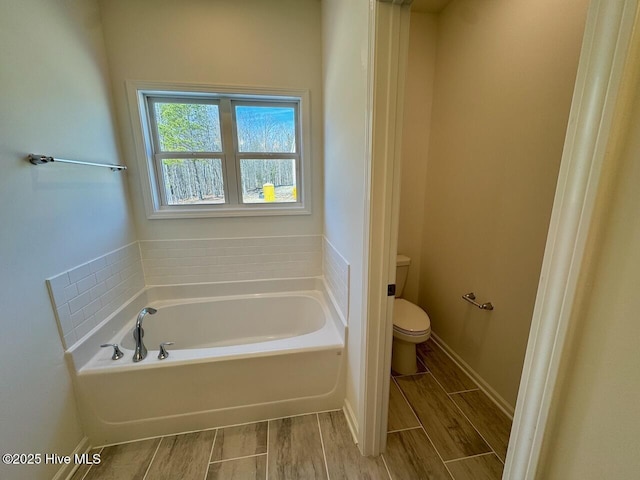 full bathroom featuring toilet, a garden tub, wood tiled floor, and baseboards