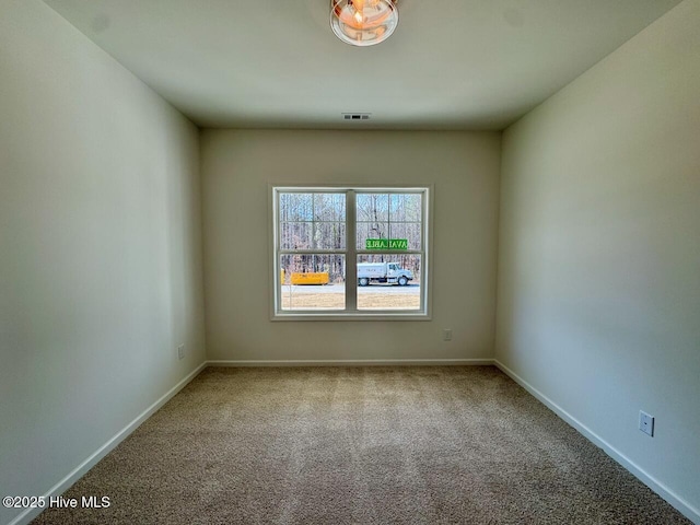 spare room with carpet floors, visible vents, and baseboards