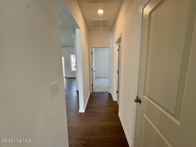 hall featuring attic access, dark wood-style flooring, visible vents, and baseboards