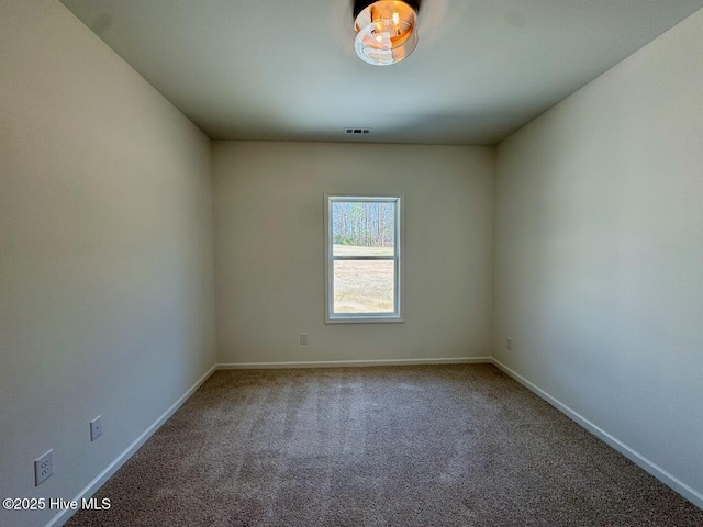 empty room featuring carpet flooring, visible vents, and baseboards