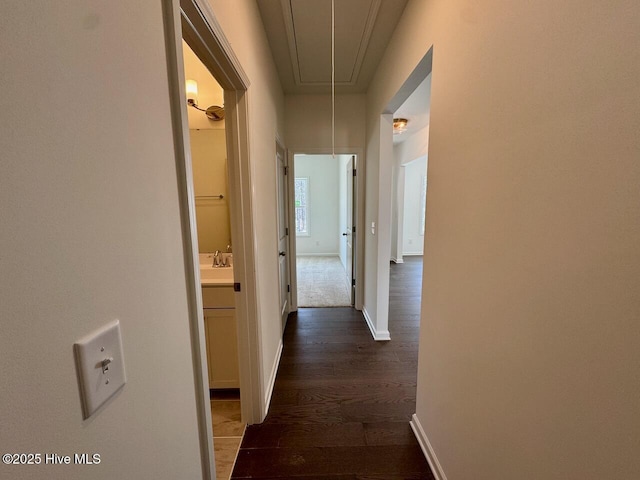 hallway featuring dark wood finished floors, attic access, and baseboards