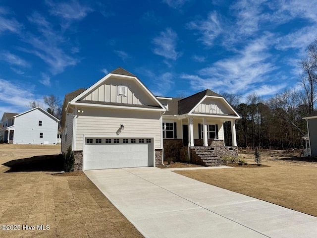 view of front of property with a porch, an attached garage, stone siding, concrete driveway, and board and batten siding