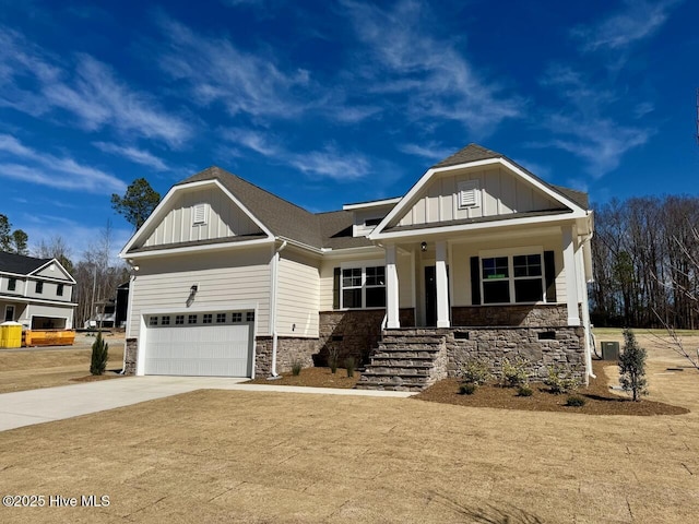 craftsman inspired home with board and batten siding, stone siding, a porch, and driveway