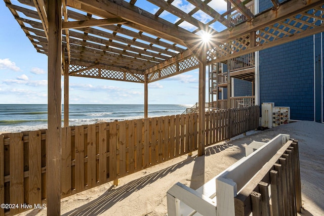 view of patio / terrace with a beach view, a pergola, and a water view